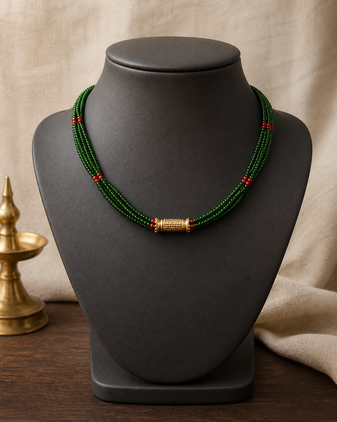 Short Kanchi Tilhari with red and green potey strands and a small gold-plated cylinder