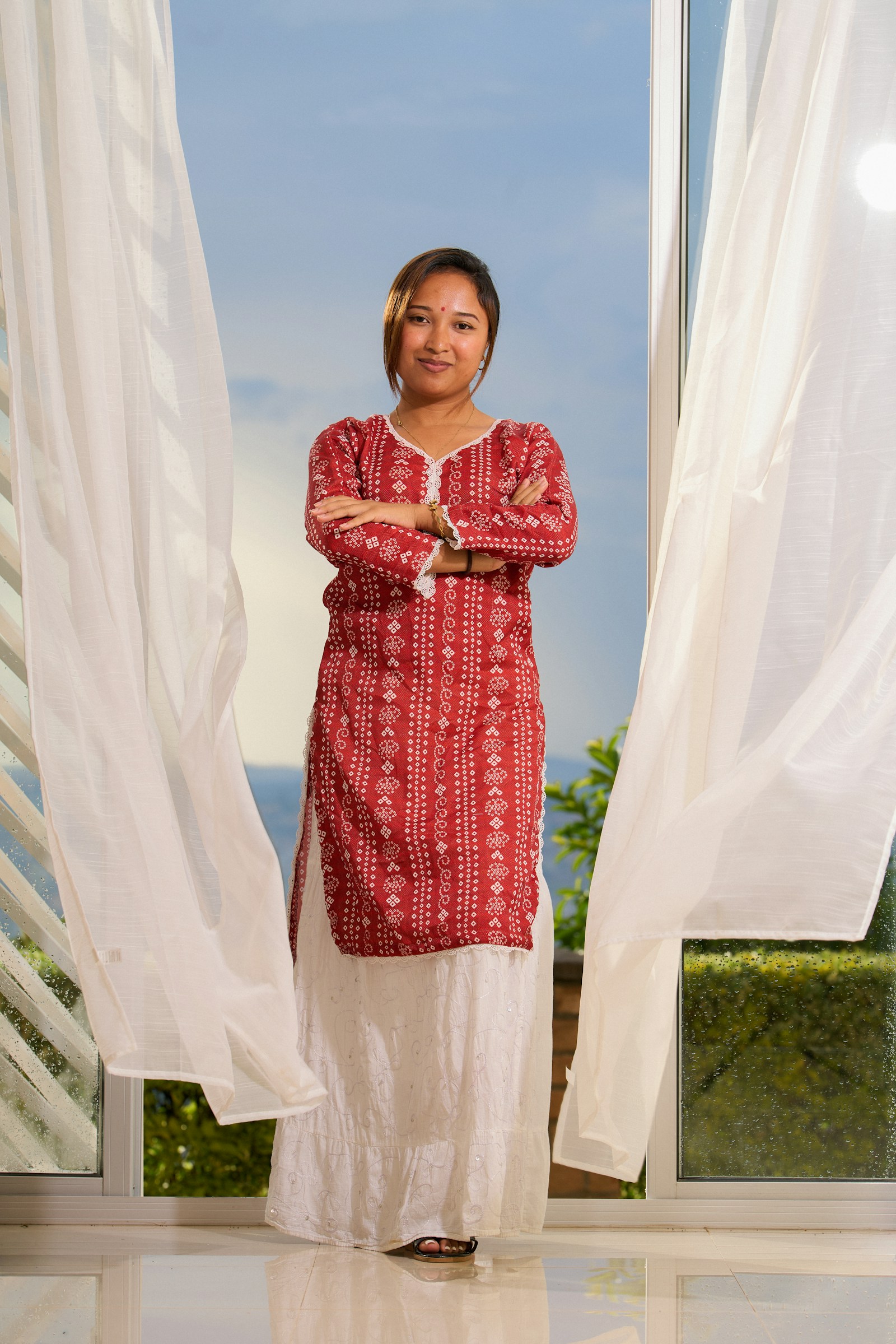 Woman wearing a red bandhani-style kurta with an ivory skirt